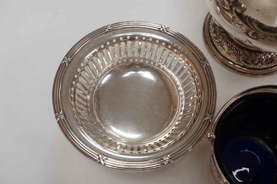 A George III small silver sugar basket, London, 1810, with blue glass liner, 57mm, a George III silver sifter spoon, a pair of silver bonbon dishes and an Edwardian small rose bowl, 16.9oz. Condition - poor to fair to go